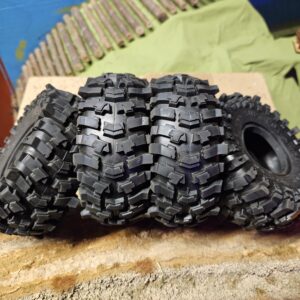 A set of four aggressive 1.9 inch budget Super Swamper clone RC crawler tires showing deep mud shedding tread lugs.