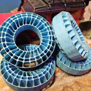 Waterproof blue medium compound Injora silicone rubber 1.9 tire inserts showing the internal supportive web structure next to mounted wheels.